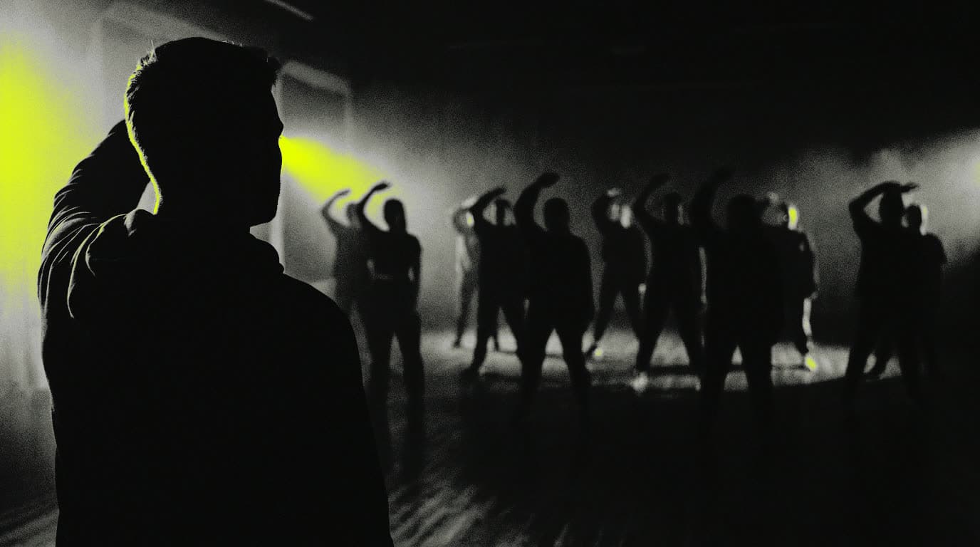 A STEPFIT instructor in silhouette cueing the next count, seen from the back of a dark room