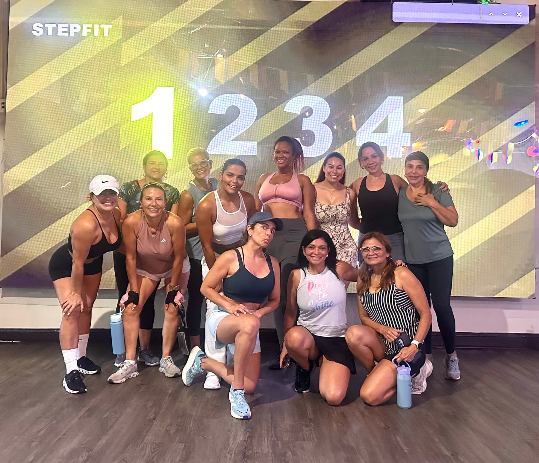 A group leaning in together in front of a projection of the numbers 1 2 3 4 with STEPFIT in the corner.