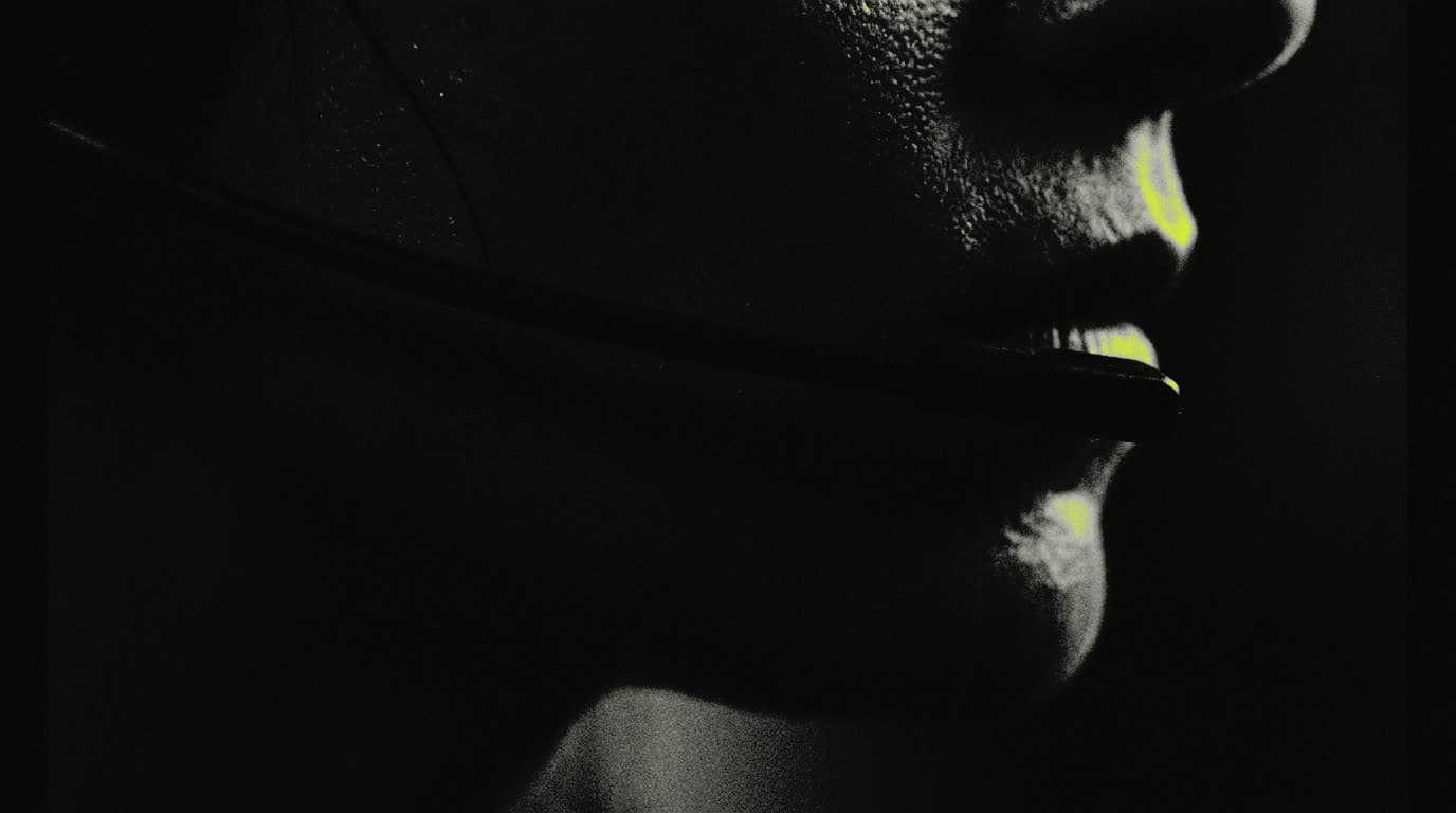 A headset microphone along a jaw, rim-lit in a dark room